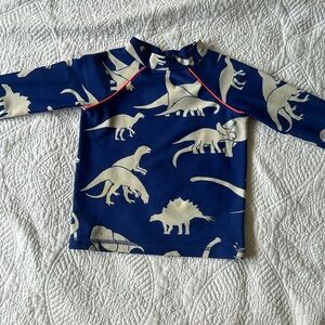 Mini Boden boys rashguard. Royal blue background with ivory dinosaurs .Size 2/3